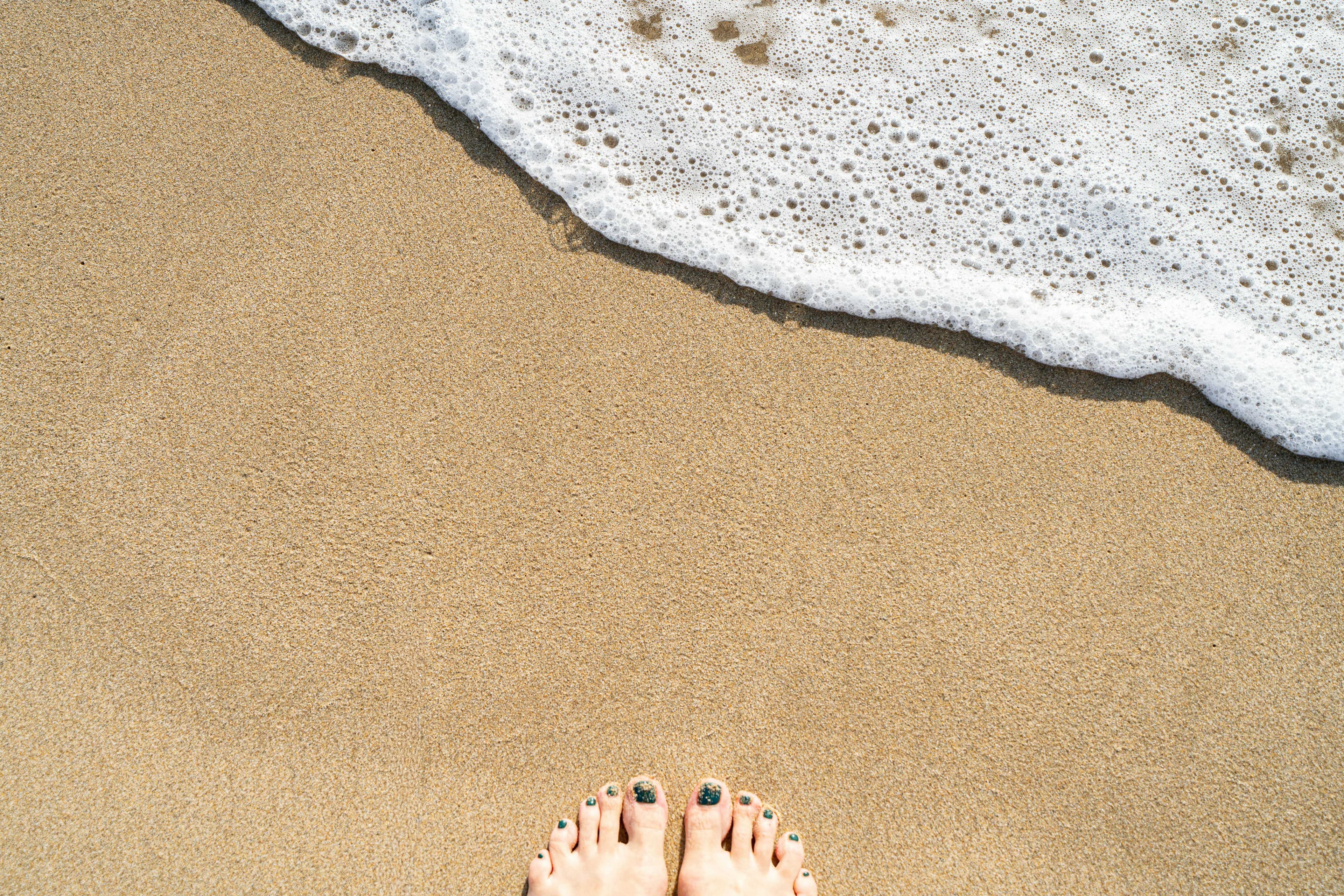 pedicured feet on a sandy beach